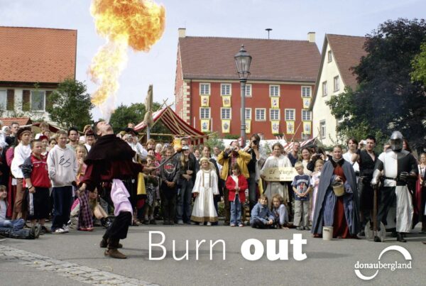 Donaubergland Postkartenmotiv mit Feuerspucker vor größerem Publikum.