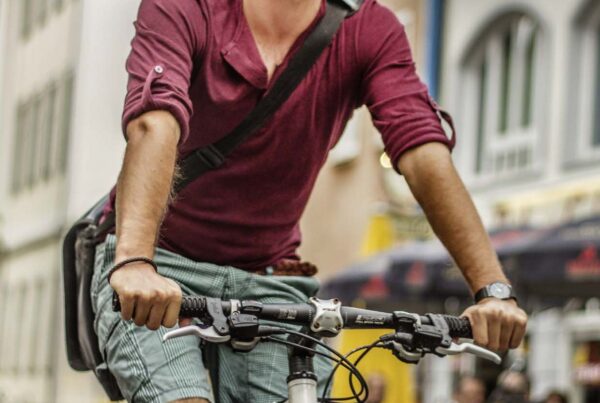 Donaubergland Postkartenmotiv mit Mann auf Fahrrad mit Umhängetasche fahrend durch Straße.