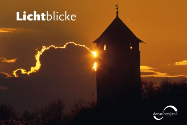 Donaubergland Postkartenmotiv mit einem Turm im tiefen Abendrot. Die Sonne wird von Wolken verdeckt und dem Schriftzug Lichtblicke