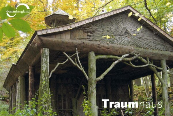 Donaubergland Postkartenmotiv mit Haus aus Baumstämmen im Wald.