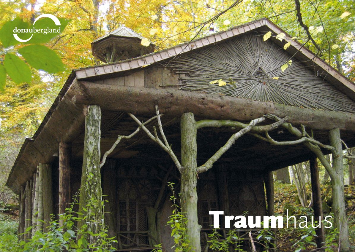 Donaubergland Postkartenmotiv mit Haus aus Baumstämmen im Wald.